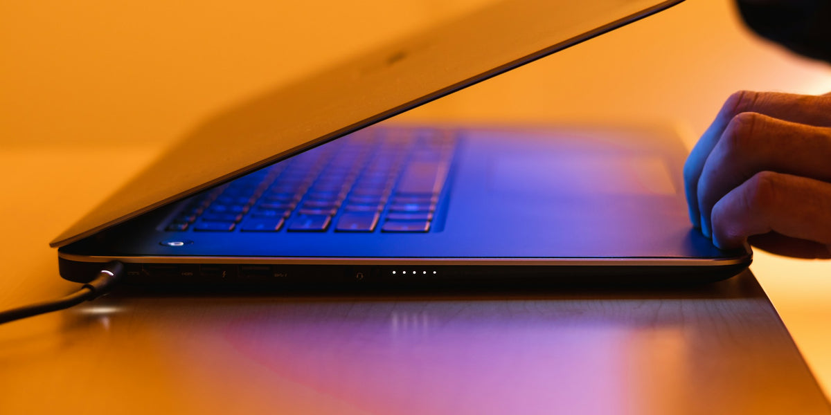 暖かな光と青い光の中でノートパソコンを開く手。Digital Solutionsのイメージ写真。Photo by Greg Rosenke on Unsplash