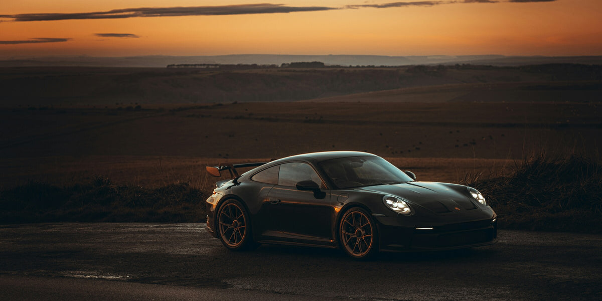 夕景の道を走る黒いスポーツカー